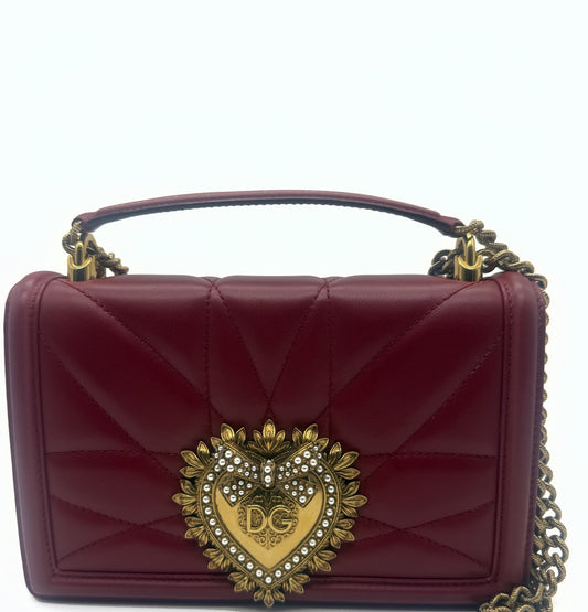 Front view of the red quilted Dolce & Gabbana Devotion bag, gold pearl Sacred Heart plaque centred, antique gold chain handle above