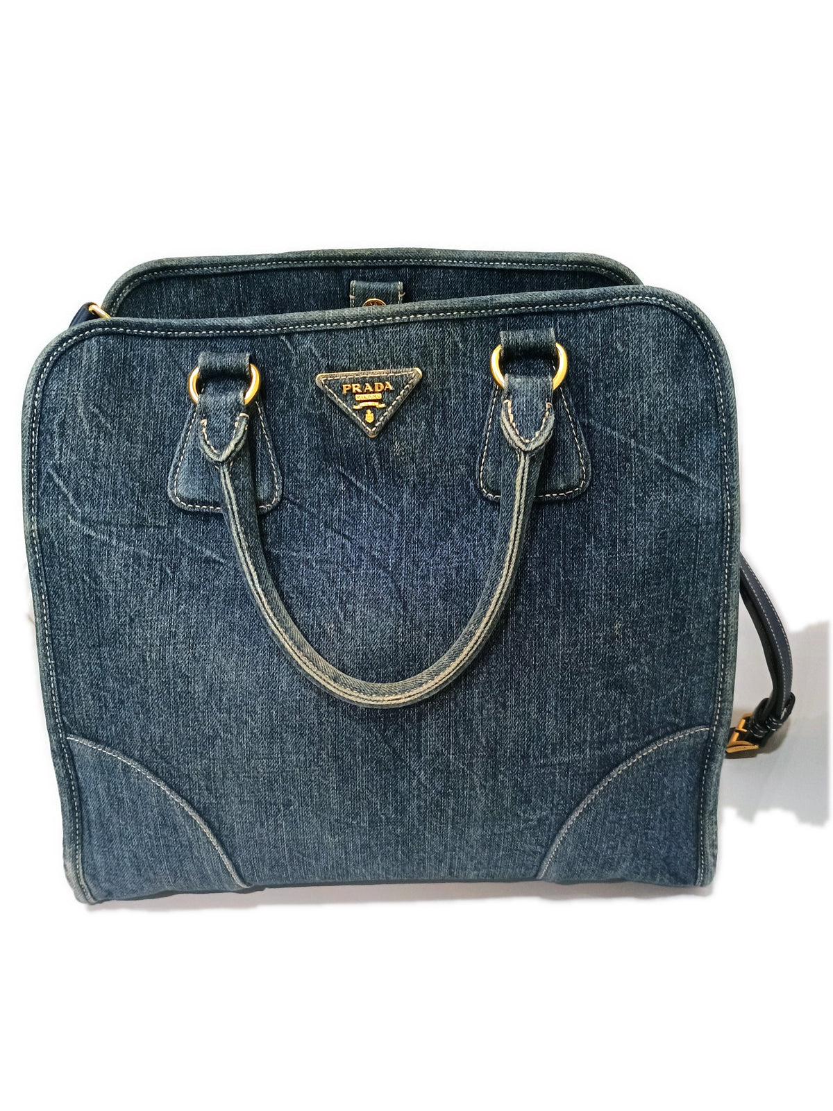 Prada denim two-way handbag in washed blue, front view with the gold PRADA MILANO plaque and rolled denim handles