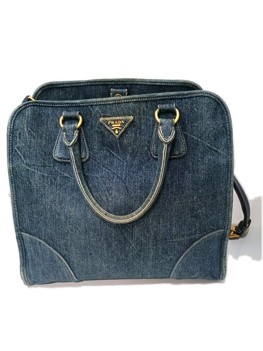 Prada denim two-way handbag in washed blue, front view with the gold PRADA MILANO plaque and rolled denim handles