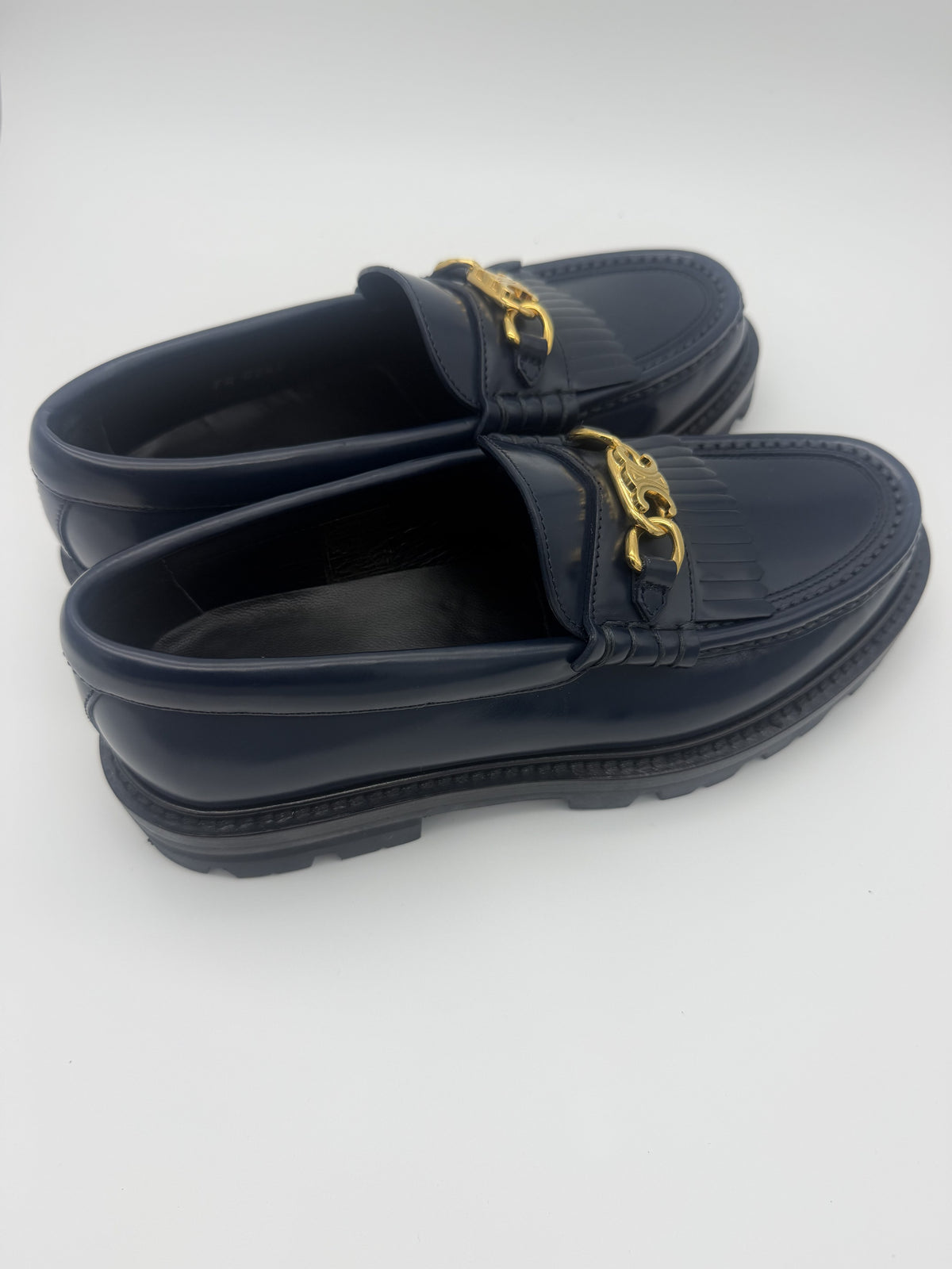 Three-quarter view of both navy Celine Margaret loafers showing the Triomphe chain and lug sole