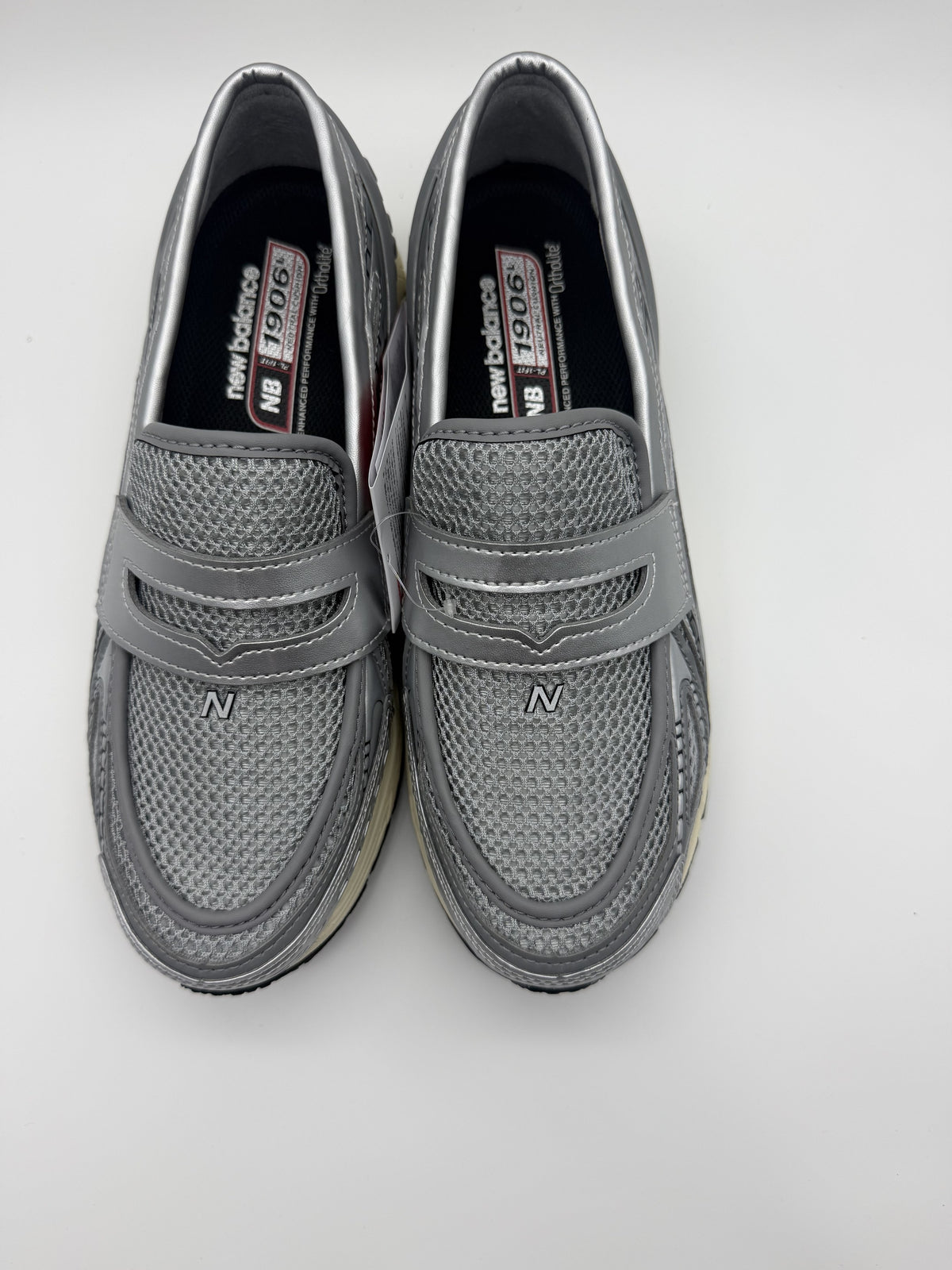 Top-down view of both loafers, silver mesh upper with penny strap