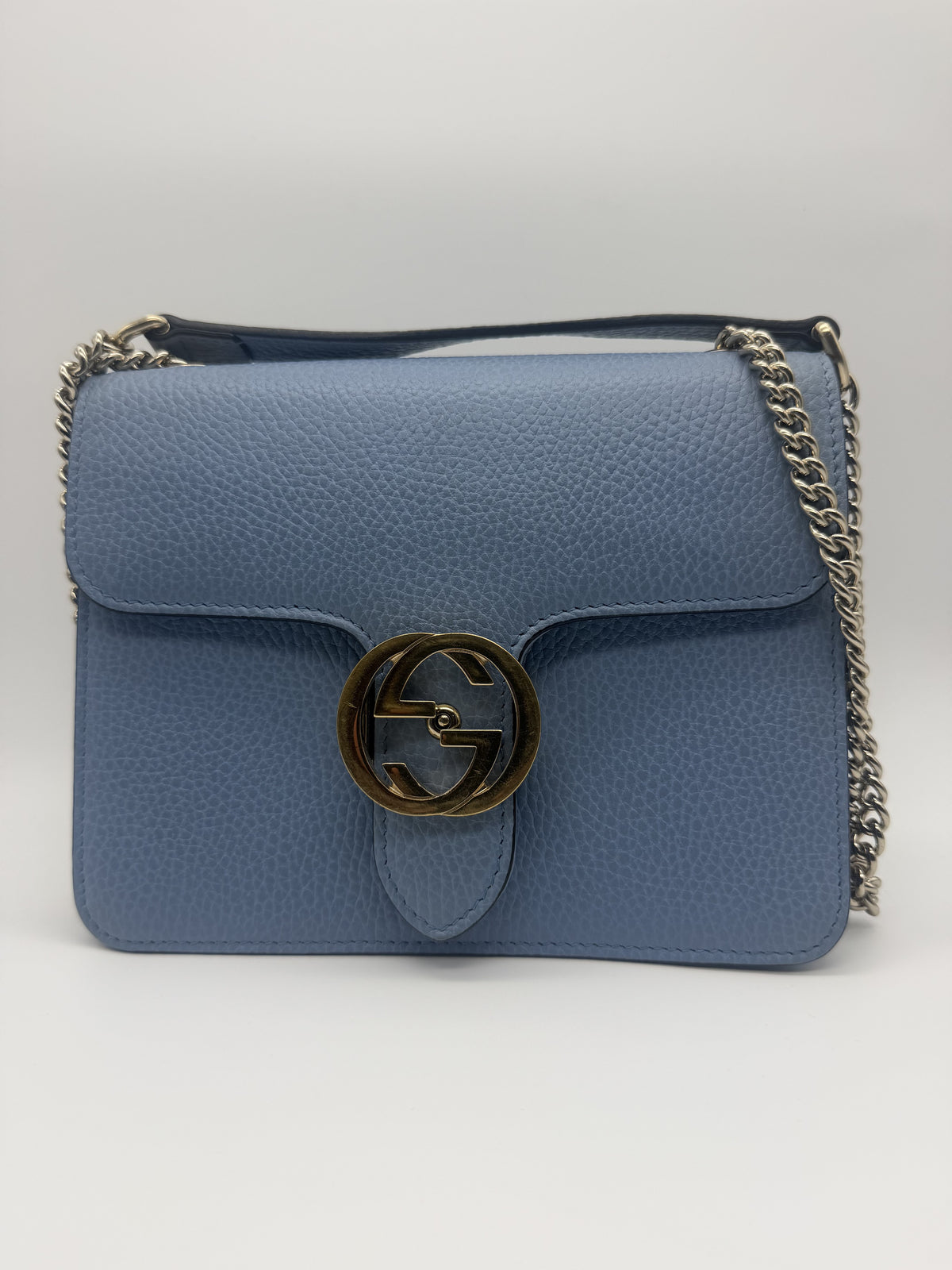 Gucci Interlocking GG Small shoulder bag in pale blue pebbled leather, front view with the aged-gold interlocking GG turnlock and silver chain
