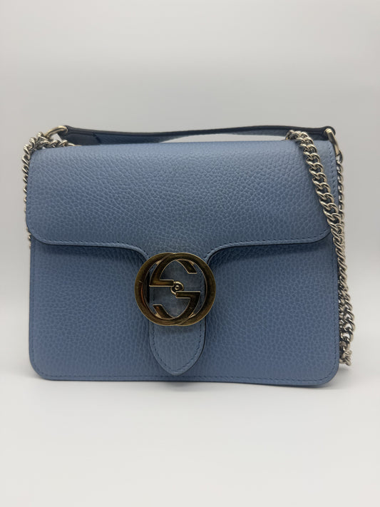 Gucci Interlocking GG Small shoulder bag in pale blue pebbled leather, front view with the aged-gold interlocking GG turnlock and silver chain