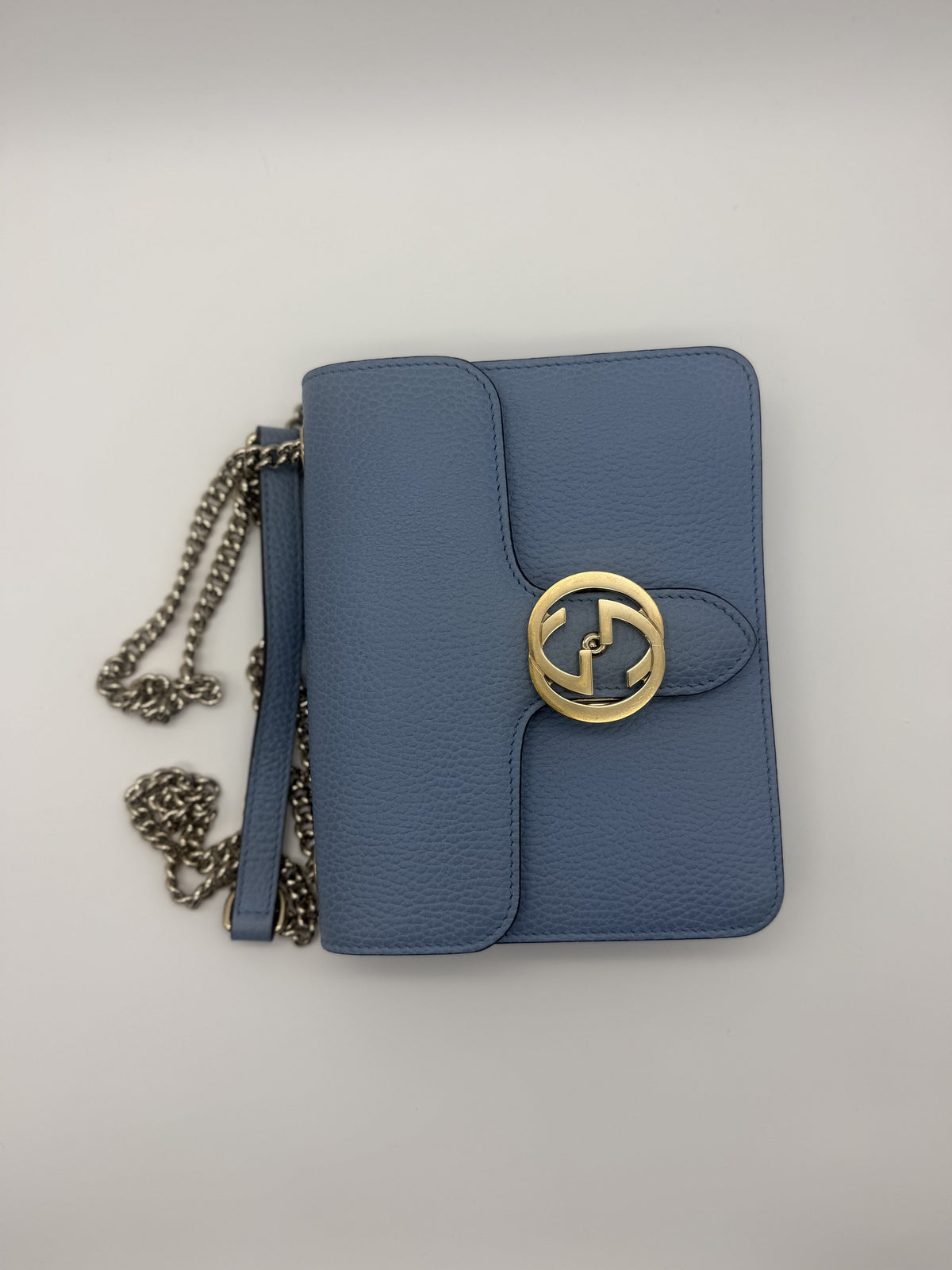 Overhead view of the pale blue Gucci Interlocking GG bag showing the gold GG turnlock and coiled silver chain