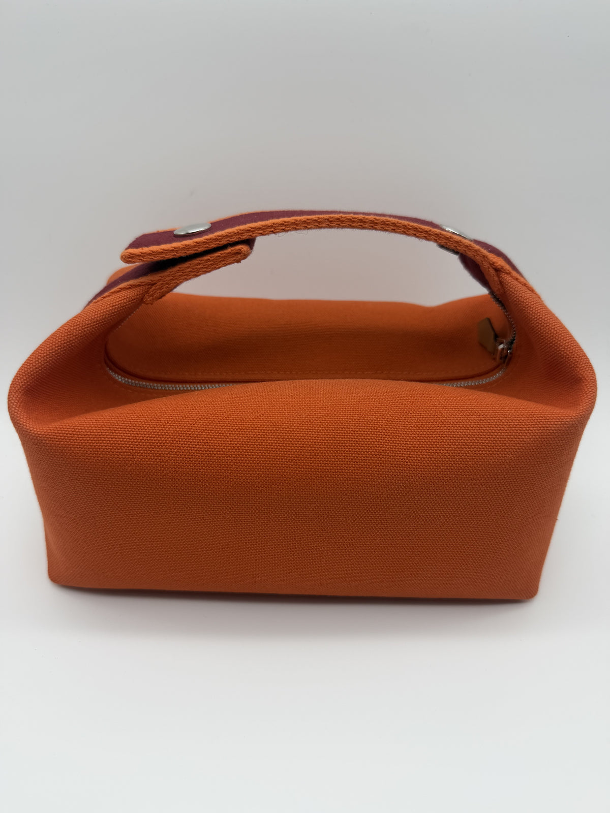 Back of the case, plain orange canvas with the strap fastened on its palladium snap studs