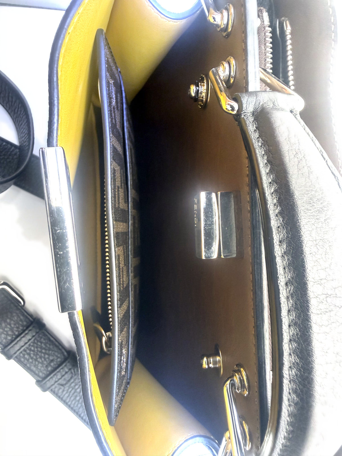 Interior of the Fendi Peekaboo showing the yellow leather lining, FF-embossed slip pocket and the reverse of the twist lock