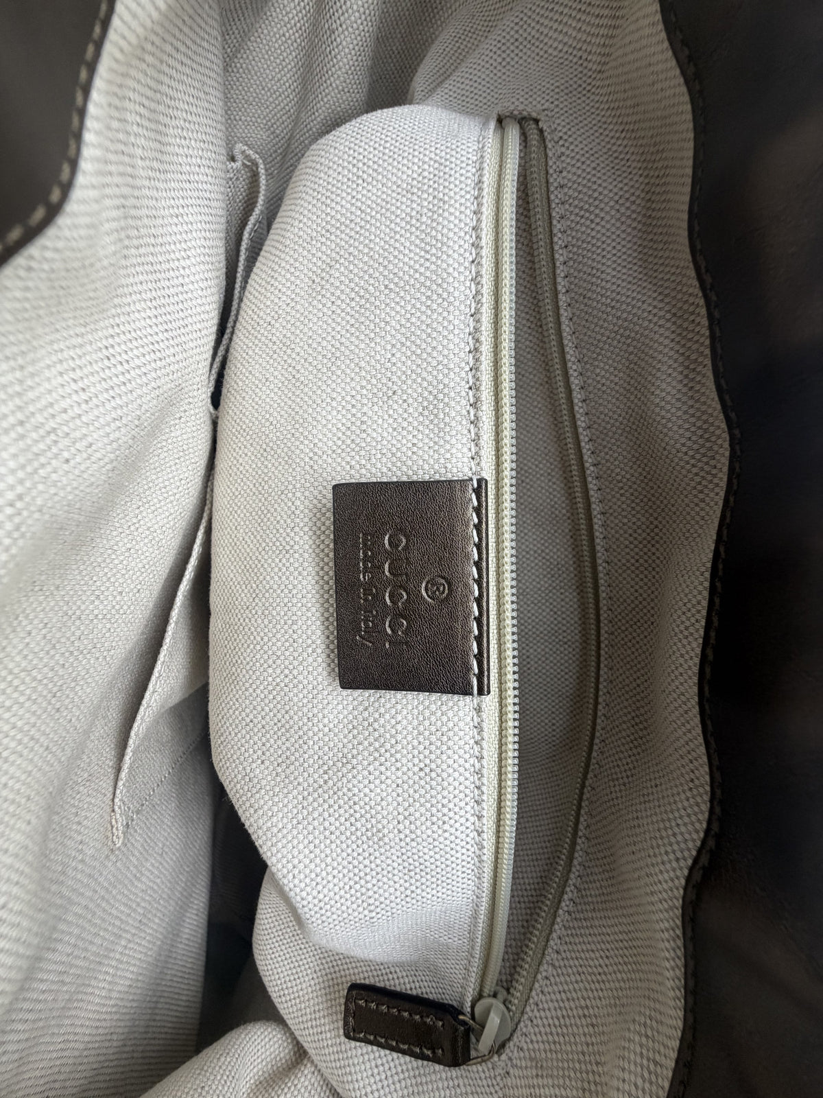Interior cream canvas lining with the gucci made in Italy leather tab and zip pocket