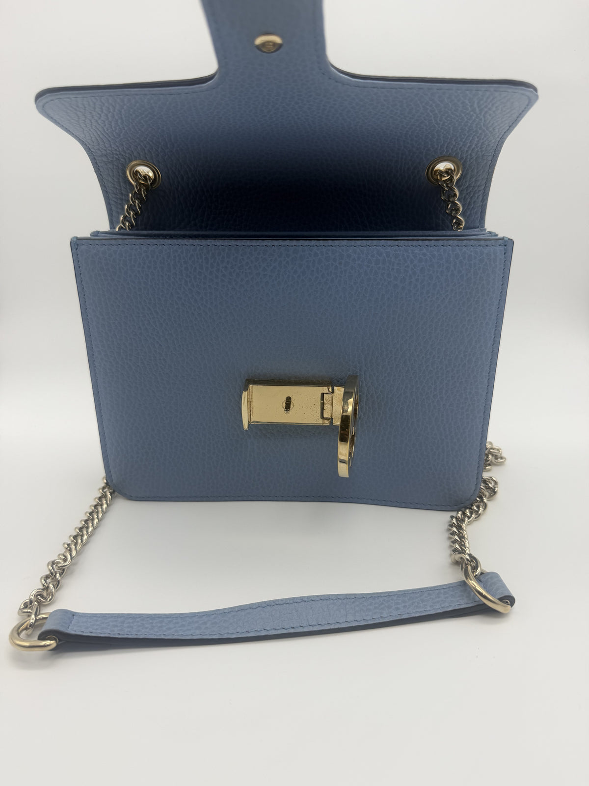 The flap open, showing the reverse of the interlocking GG turnlock and the pale blue leather body